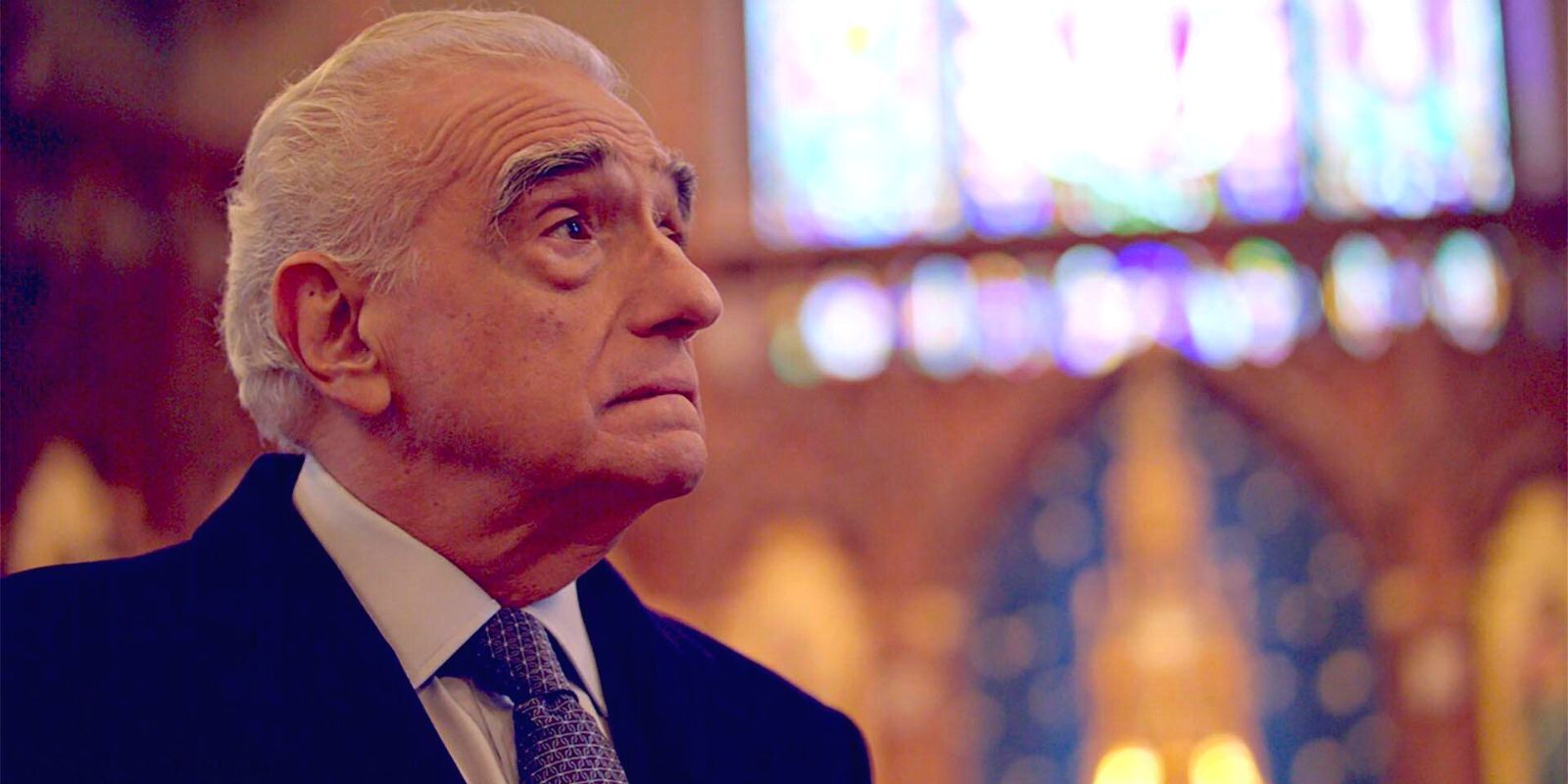 Martin Scorsese luce pensativo en una catedral borrosa vestido con traje y corbata