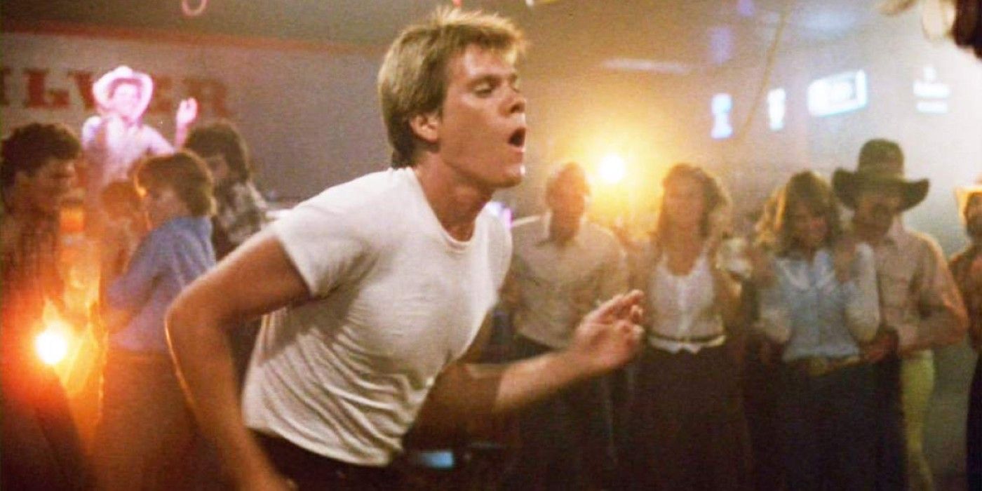 Kevin Bacon con una camisa blanca bailando frente a una multitud en la película Footloose