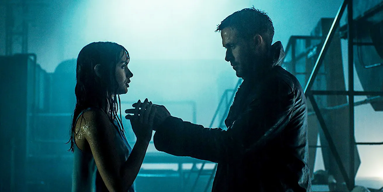 K y joi tomados de la mano bajo la lluvia, encima de un edificio en Blade Runner 2049
